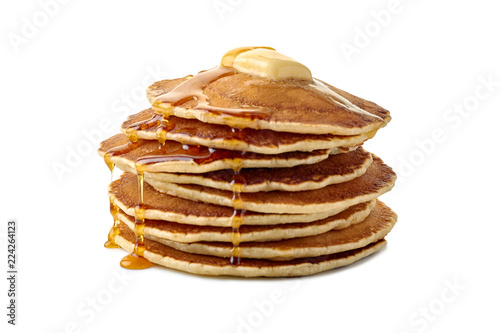 Stack of pancakes with butter and a flowing maple syrup on white