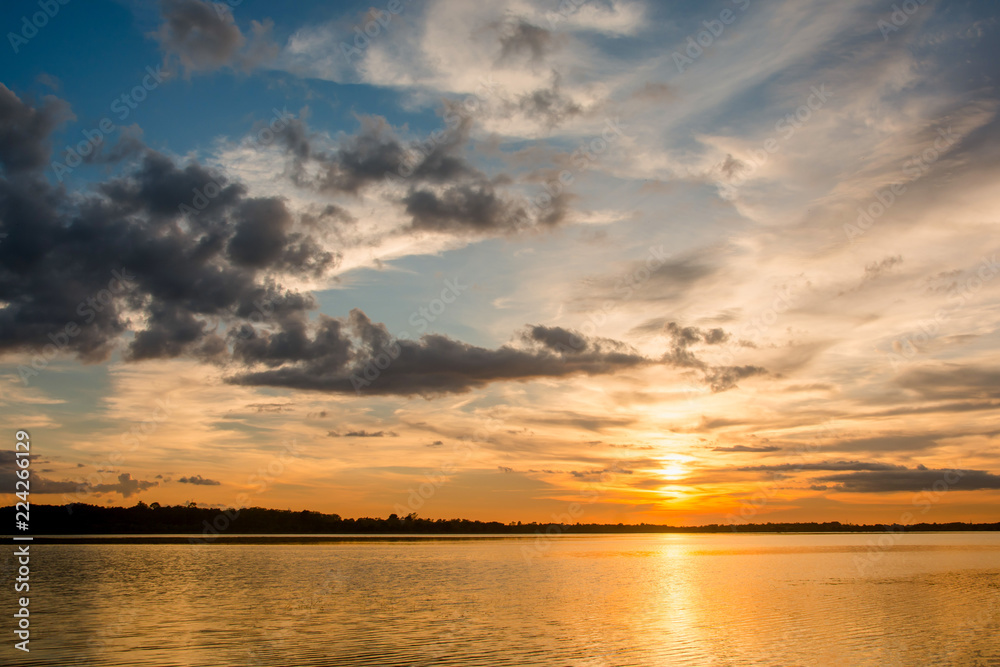 Sunset in the lake. beautiful sunset behind the clouds above the over lake landscape background. dramatic sky with cloud at sunset