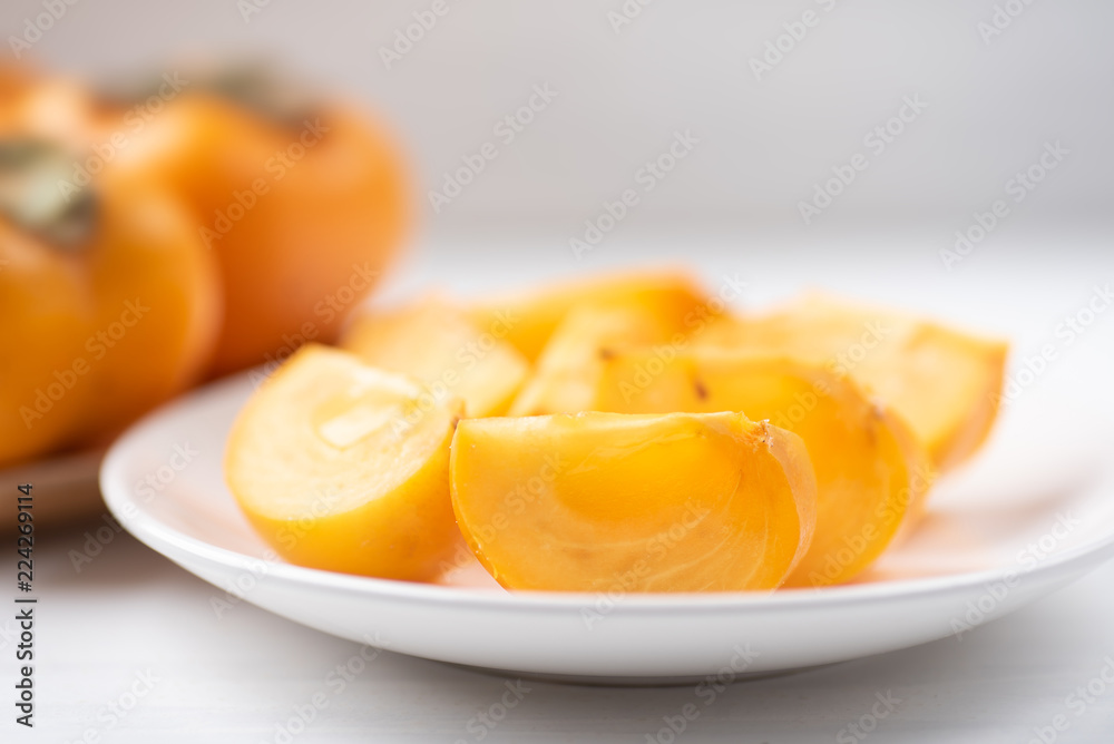 Sliced persimmon fruit on white dish, healthy fruit