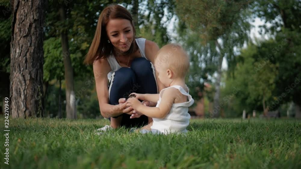 Portrait of happy family - baby boy sits in the park while parents watch him. Concept Family relaxation. Portrait of happy family - baby boy sits in the park while parents watch him. Concept Family relaxation.
