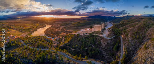Aerial sunrise view of Miravet templar crusader castle and ebro river province of tarragona Spain with orange, purple, blue sky. Miravet is one of the most picturesque villages in Spain. photo
