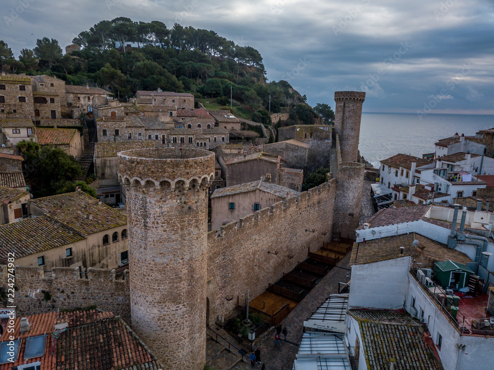 Aerial view of popular Costa Brava vacation beach town Tossa de Mar near Barcelona Spain with medieval walls, towers and stormy cloudy sky in the background