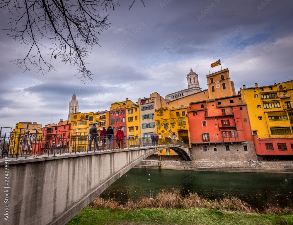 Colorful red, orange, yellow houses along the onyar river in medieval Girona, Catalonia north of Barcelona in Spain with stormy cloudy sky