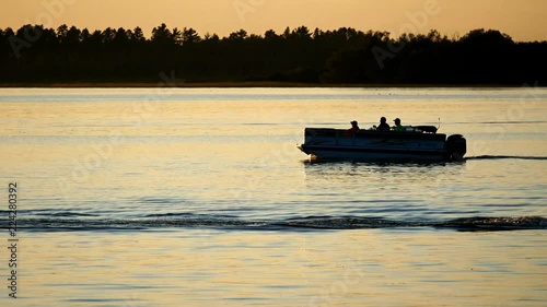 Silhouette of people enjoying boating on a calm lake in Bemidji, Minnesota at sunset. Two Pontoon boats.