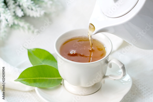 Slika na platnu Close up pouring hot black tea in a white tea cup ,  Tea ceremony time concept