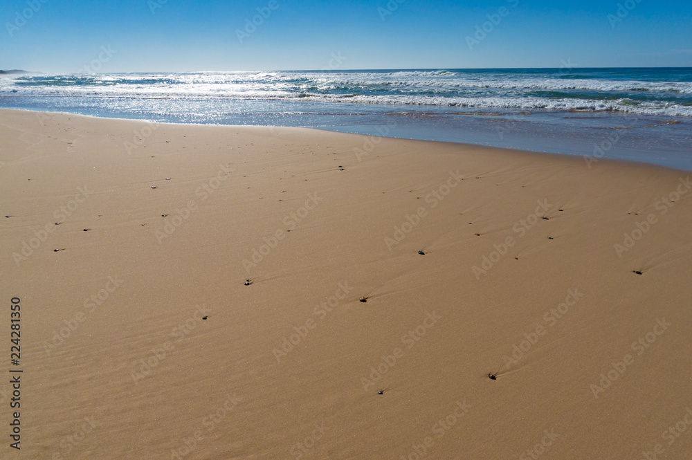 Low angle view of beach sand with pebbles and mild waves Low angle view of beach sand with pebbles and mild waves