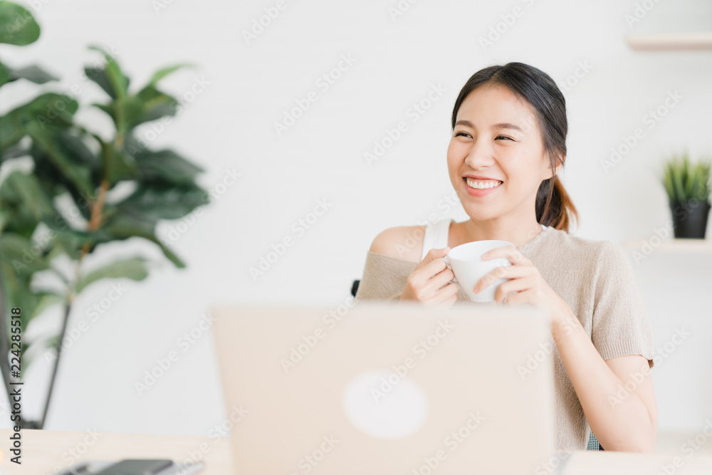 Beautiful young smiling asian woman working on laptop and drinking coffee in living room at home. Asia business woman working document finance and calculator in her home office. Enjoying time at home. Beautiful young smiling asian woman working on laptop and drinking coffee in living room at home. Asia business woman working document finance and calculator in her home office. Enjoying time at home.