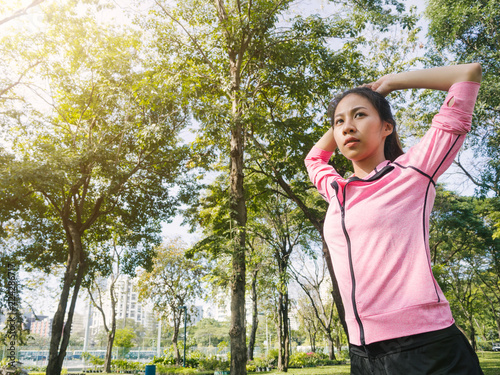 Asian young woman warm up the body stretching before morning exercise and yoga in the park under warm light morning. Healthy young asian woman exercising at park. Woman exercise outdoor concept.