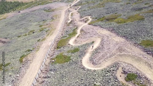 Young man biking downs curving on a dowhill biking track in Lapland Finland. photo