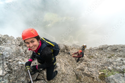 three young attractive male and female mountain climbers on a steep and exposed Via Ferrata in Alta Badia in the South Tyrol in the Italian Dolomites