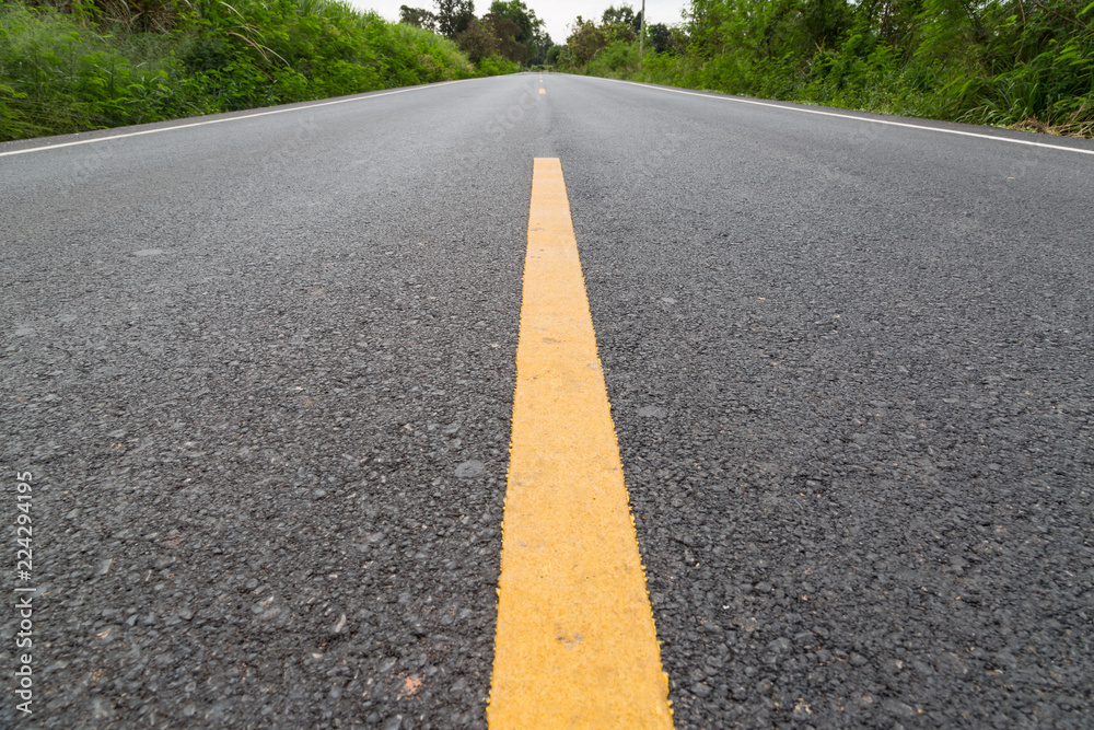 The yellow line on the road with tree and sky The yellow line on the road with tree and sky