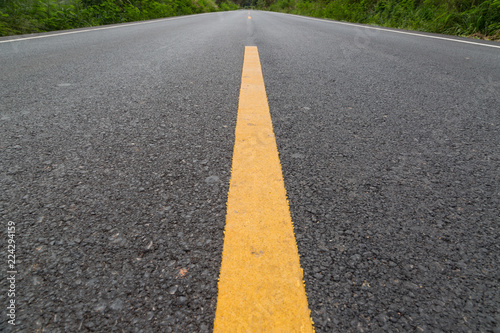 The yellow line on the road with tree and sky