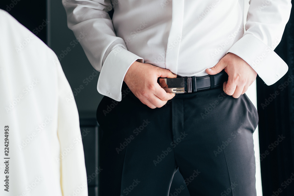 A man in black pants and a white shirt buttoned a brown leather trouser belt.  Business man Stock Photo | Adobe Stock