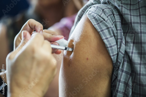 Getting flu vaccines from a doctor with an injection in the arm.