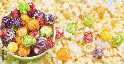 a sweet, colorful popcorn lies in a bucket and is scattered on the table