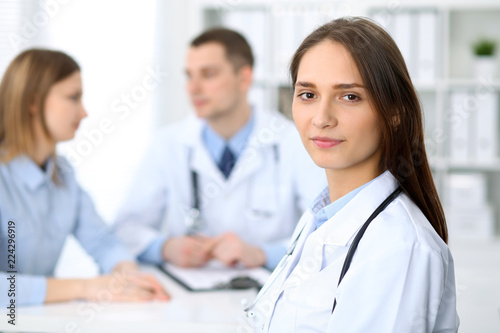 Young beautiful female doctor smiling on the background with patient in hospital