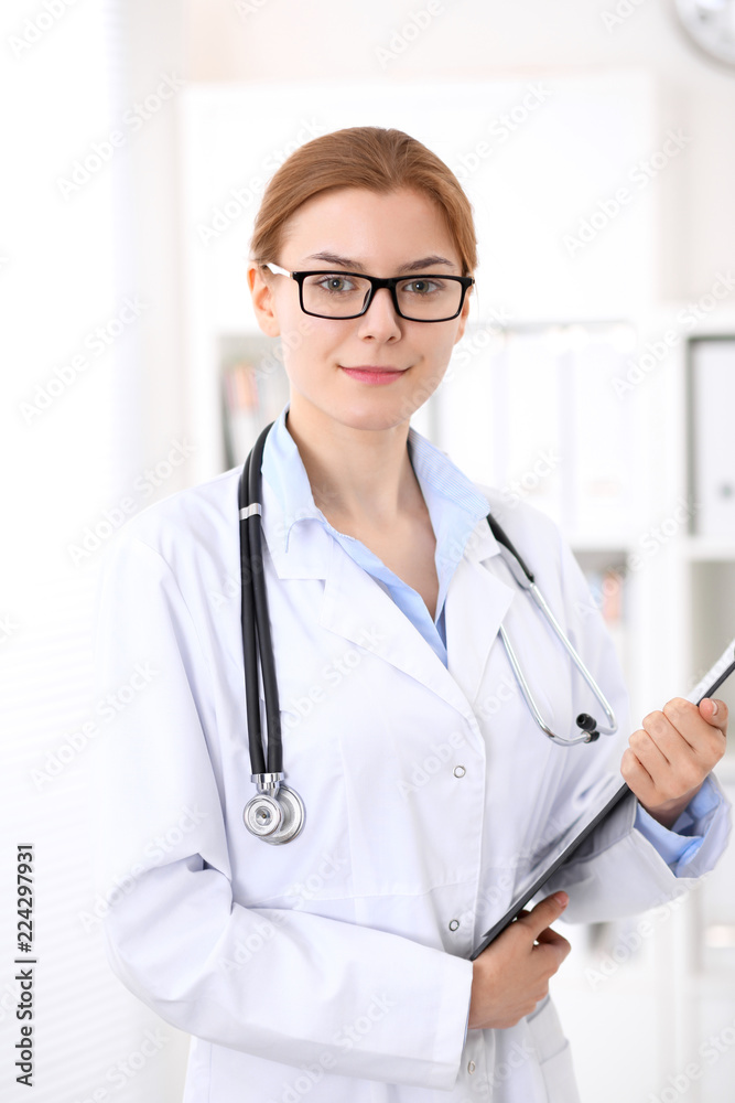 Young brunette female doctor at work in hospital. Physician ready to help. Medicine and healthcare concept Young brunette female doctor at work in hospital. Physician ready to help. Medicine and healthcare concept
