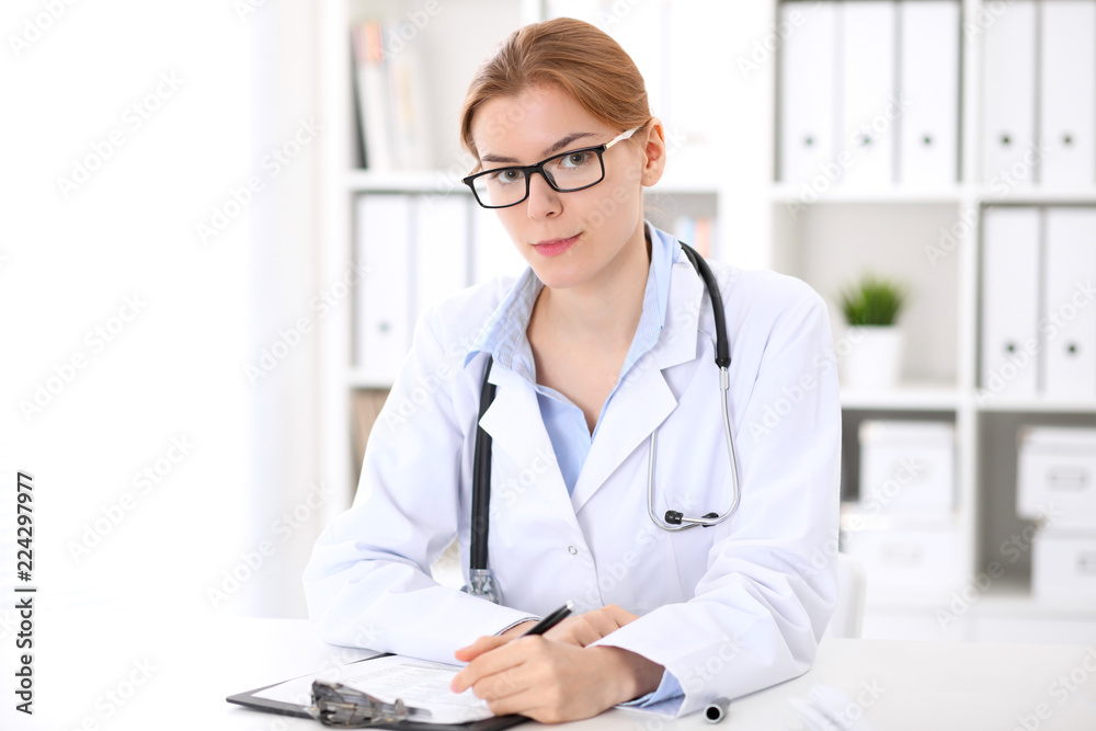 Young brunette female doctor at work in hospital. Physician ready to help. Medicine and healthcare concept Young brunette female doctor at work in hospital. Physician ready to help. Medicine and healthcare concept