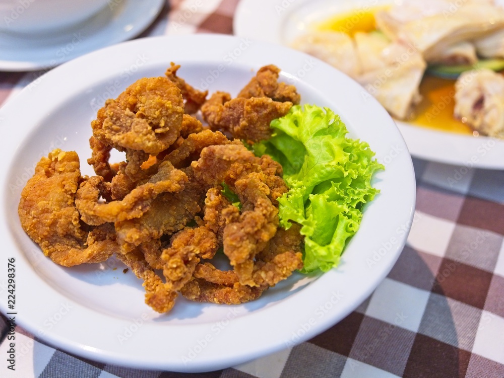 Crispy fried pork strips on a white plate decorate with green lettuce on red checked Pattern tablecloth Crispy fried pork strips on a white plate decorate with green lettuce on red checked Pattern tablecloth