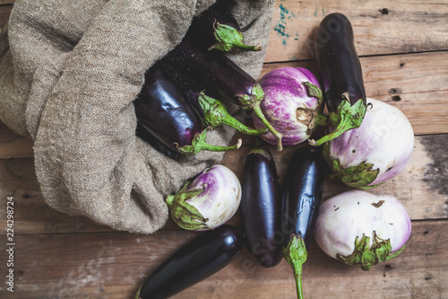 bag of blue eggplants rests on white photo