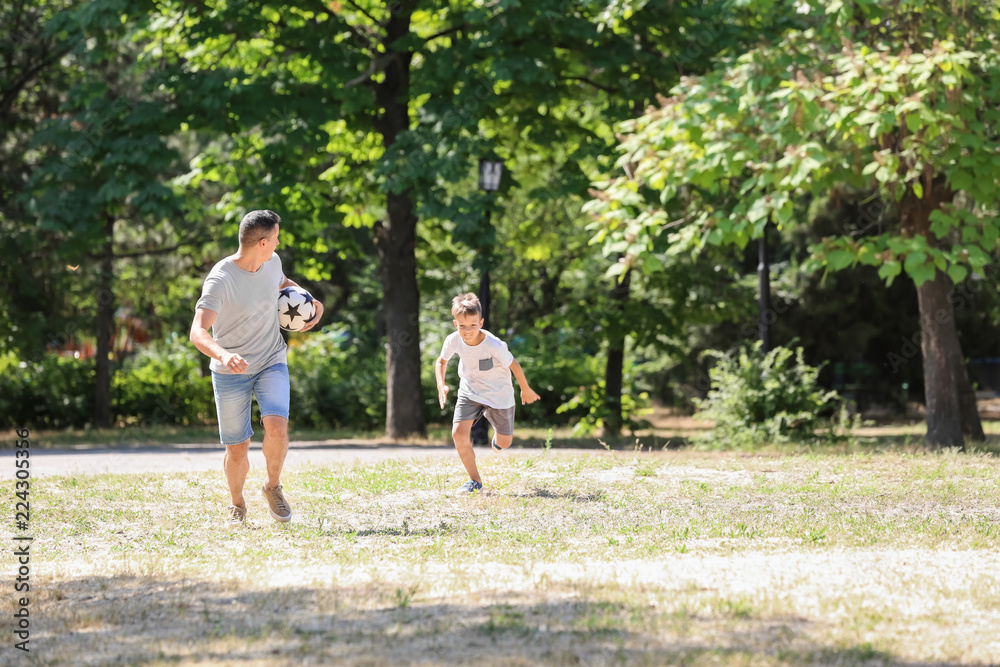 Little boy with his dad playing football outdoors Little boy with his dad playing football outdoors