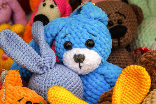 Colorful knitted handmade toys are on display for sale at a souvenir shop on the market. Close-up