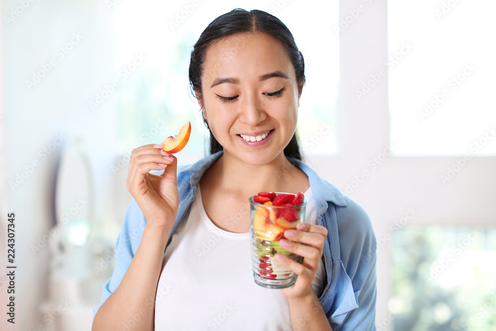 Asian woman eating healthy fruit salad at home Asian woman eating healthy fruit salad at home