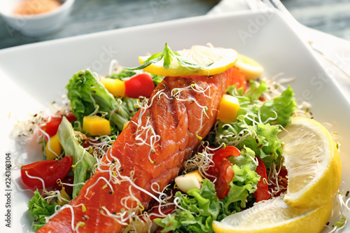 Tasty salmon with salad on plate, closeup
