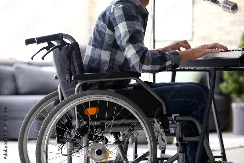 Obraz premium Young musician in wheelchair playing synthesizer at home