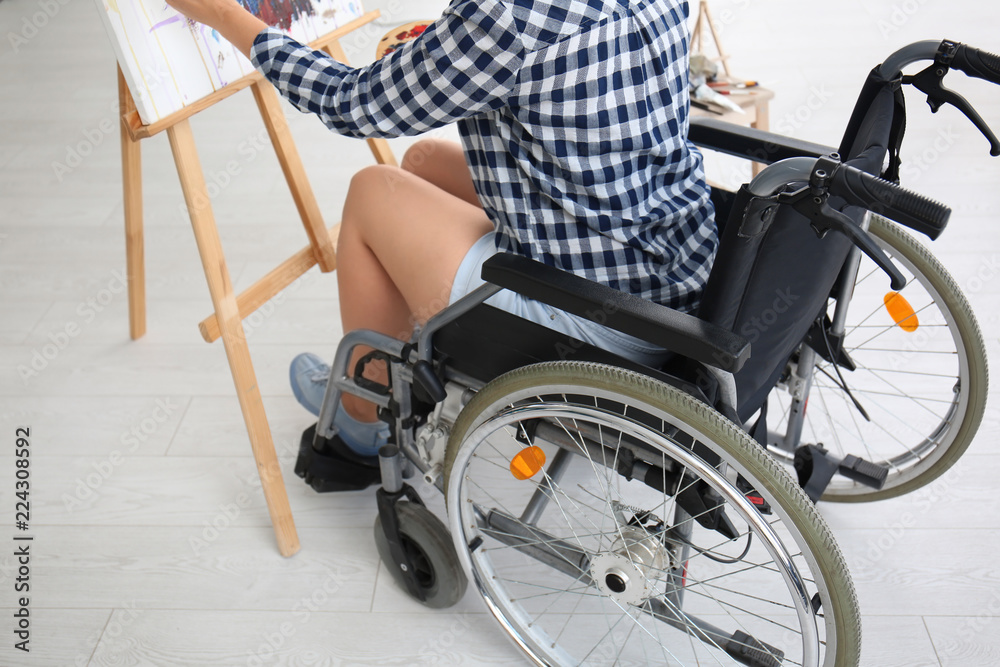 Obraz premium Young female artist in wheelchair painting picture at home