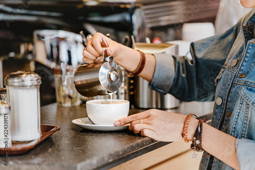 Barista pouring milk into coffee at bar counter