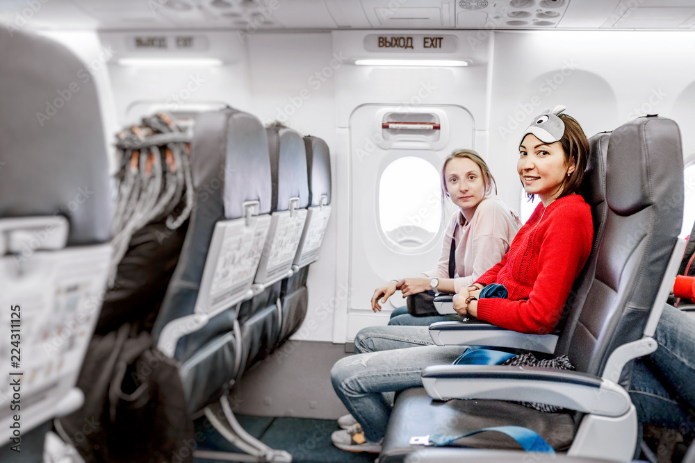 Fototapeta premium Happy Girlfriends traveling by plane together, air flight passengers
