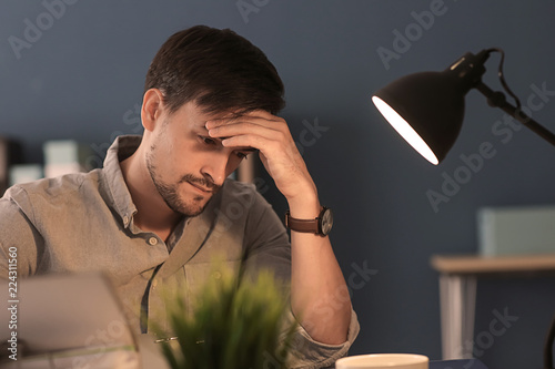 Tired man working late in e...