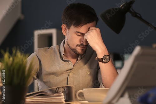 Tired man working late in e...