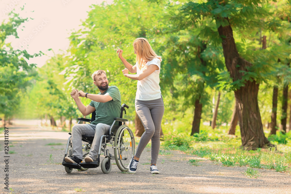 Man in wheelchair with beautiful woman dancing outdoors Man in wheelchair with beautiful woman dancing outdoors