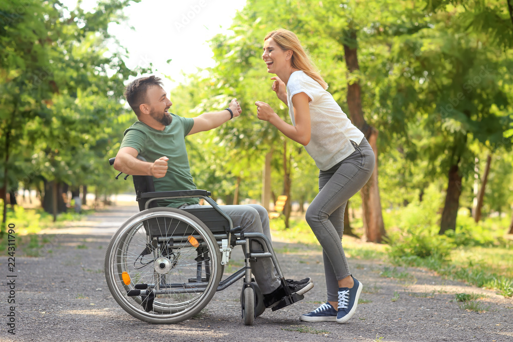 Man in wheelchair with beautiful woman dancing outdoors Man in wheelchair with beautiful woman dancing outdoors