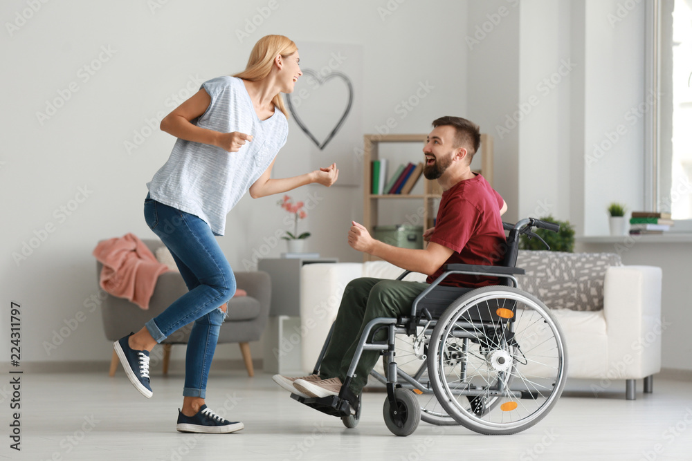Man in wheelchair with beautiful woman dancing at home Man in wheelchair with beautiful woman dancing at home