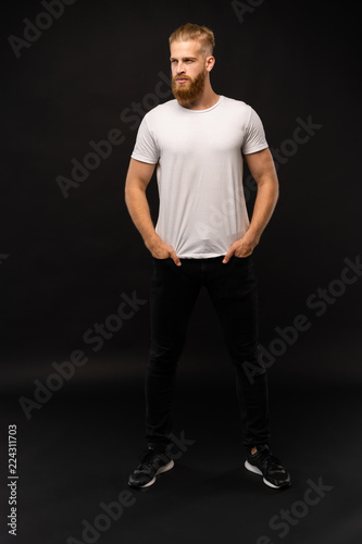 Full length portrait of a happy casual man standing isolated on a gray background.