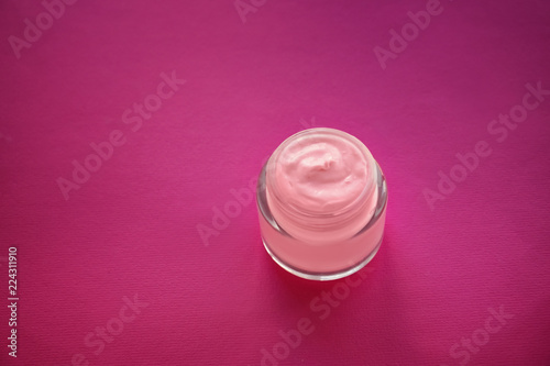 Jar with body cream on color table