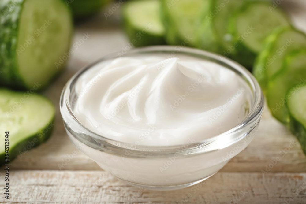 Bowl with cucumber body cream on wooden table, closeup Bowl with cucumber body cream on wooden table, closeup