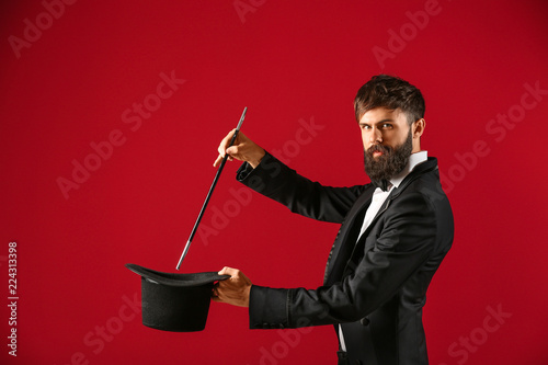 Fotografia Magician showing tricks with hat on color background