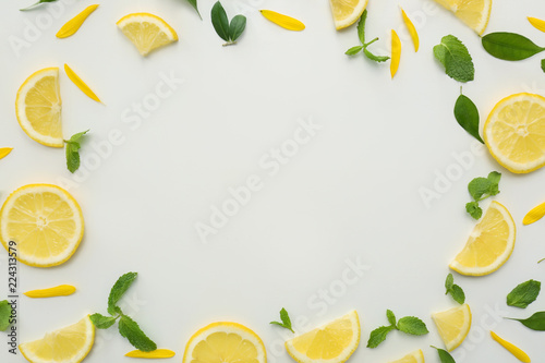 Frame made of lemon slices and green leaves on white background