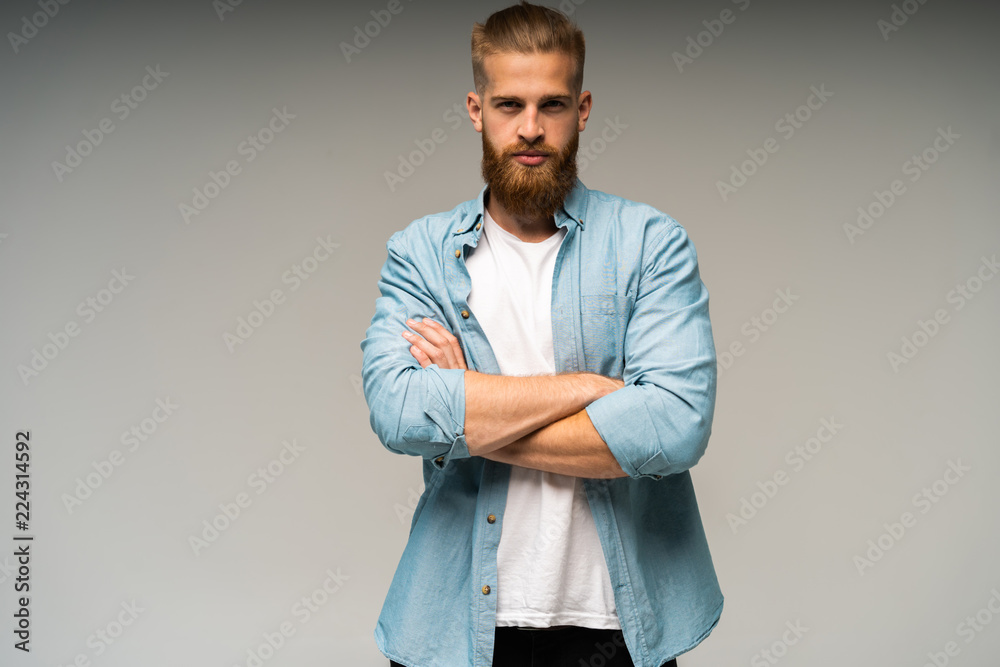 Fototapeta premium Portrait of happy fashionable handsome man in jeans shirt crossing hands and look at camera.
