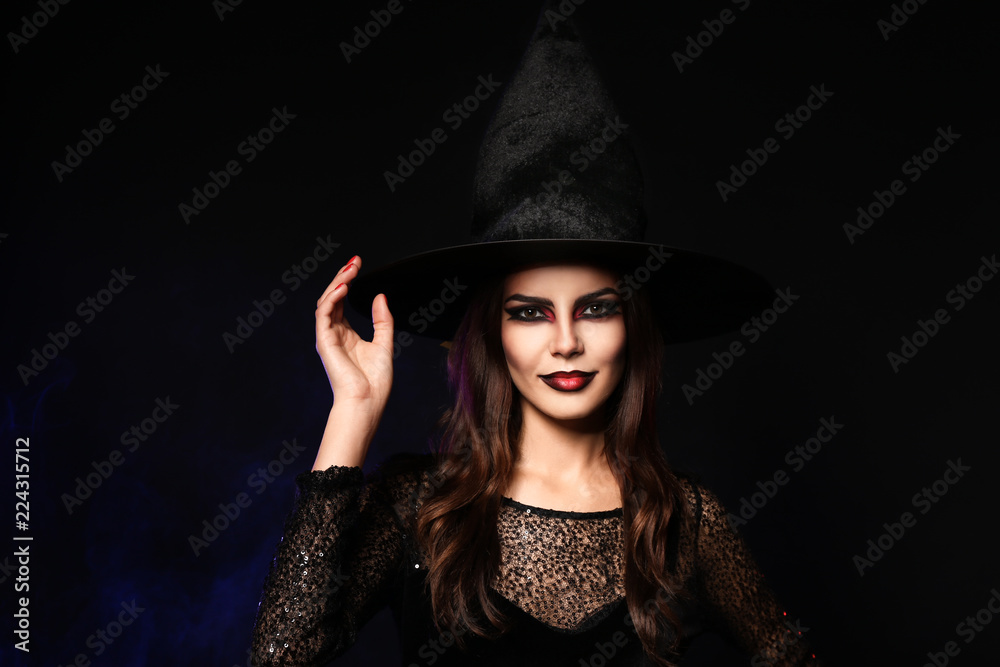 Beautiful woman dressed as witch for Halloween on dark background Beautiful woman dressed as witch for Halloween on dark background