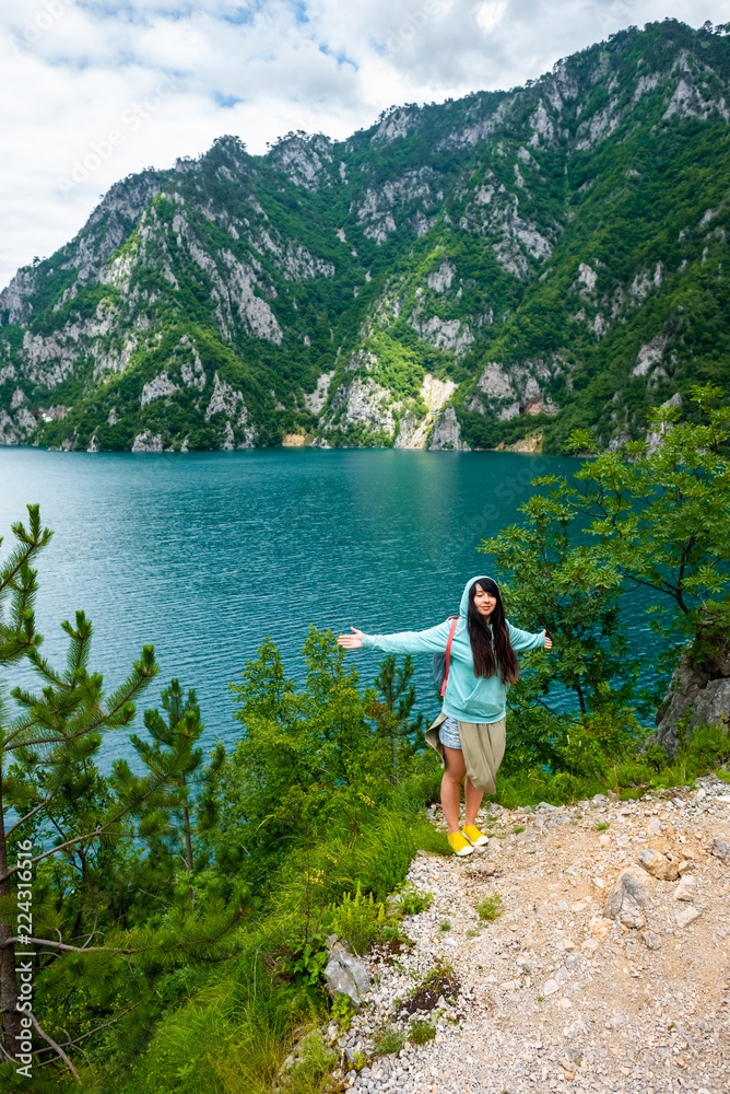 beautiful woman standing with open arms near Piva Lake (Pivsko Jezero) in Montenegro