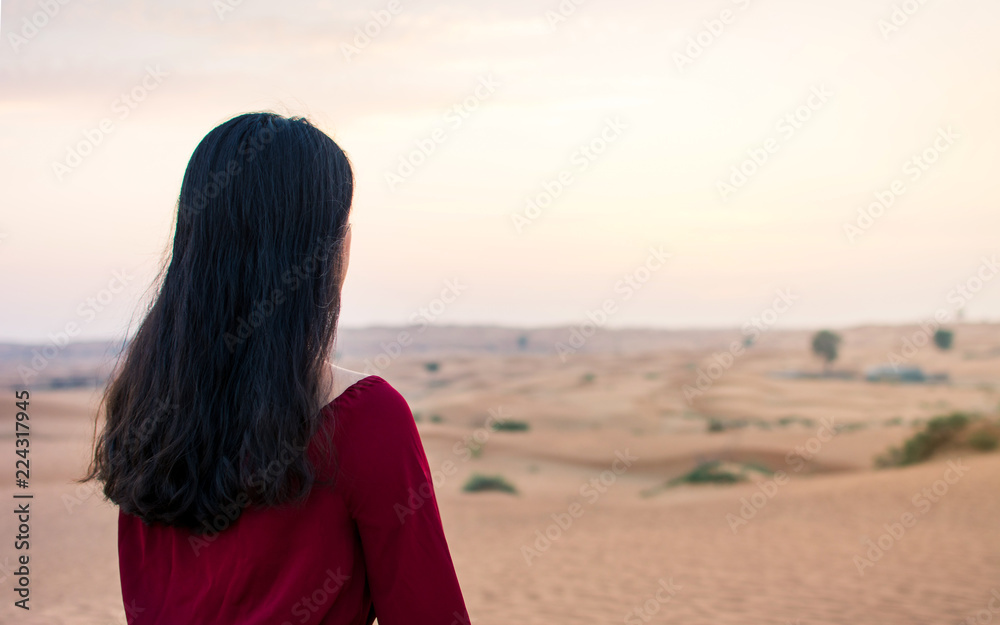 Fototapeta premium Woman walking in the desert at sunset