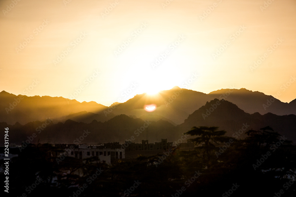 the yellow  orange  mountains with white hotels and palms in egypt at sunset background with sun