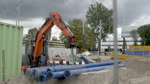 An excavator at a construction site in Amsterdam. The Amstel station is being renovated, new tramlines are build. A slow pan to the right. photo