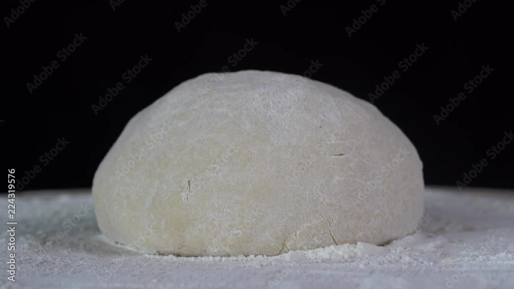 Fresh raw dough on black background, close up, rotates on kitchen table. Fresh raw dough for pizza or bread Fresh raw dough on black background, close up, rotates on kitchen table. Fresh raw dough for pizza or bread