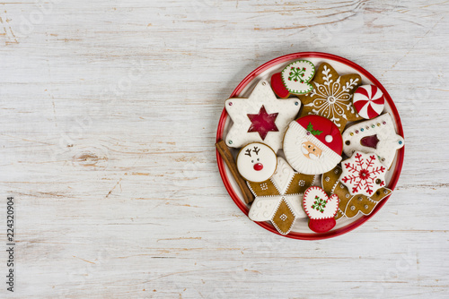 Plate with various colorful christmas gingerbread isolated on wooden background